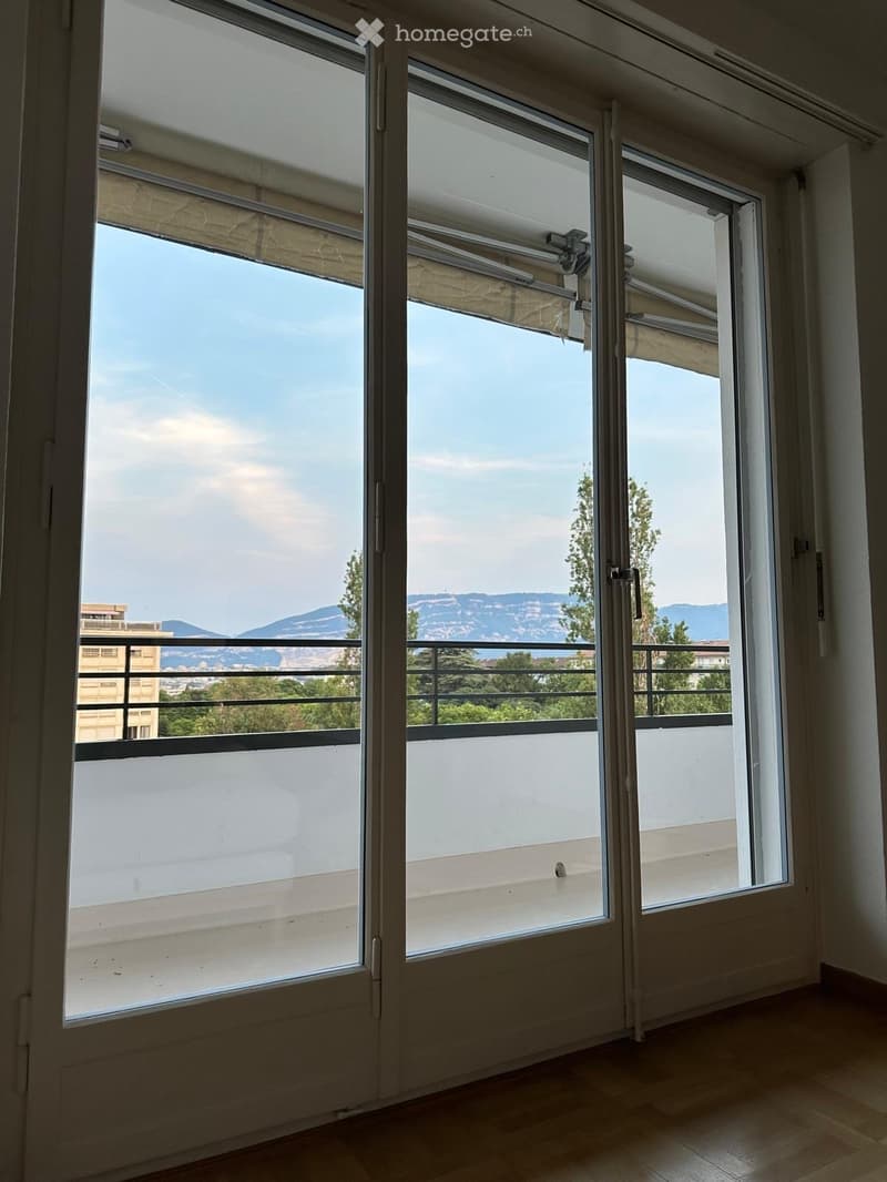 Empty room with large sliding glass doors opening to a balcony, offering a scenic mountain view.