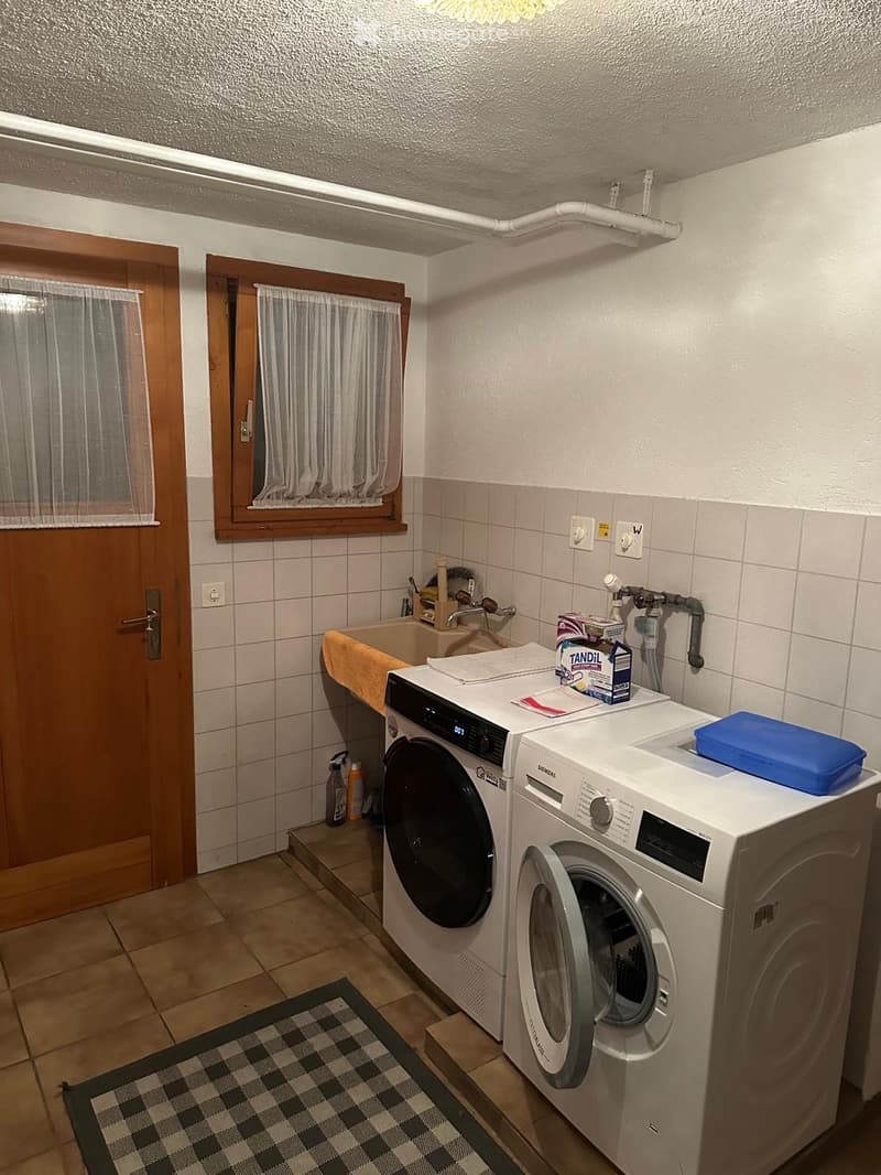 Bathroom with a washing machine, dishwasher, sink, and various items on the counter.
