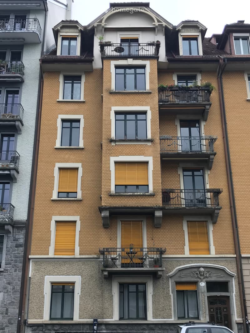 Multi-story brick building with multiple balconies, large windows, and decorative architectural details.