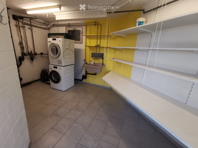 Utility room with tiled floor, white shelves, washing machine, dishwasher, and a small sink.