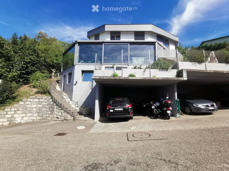 Modern two-story house with a large garage, multiple vehicles inside, and a raised ground floor with a staircase leading up.