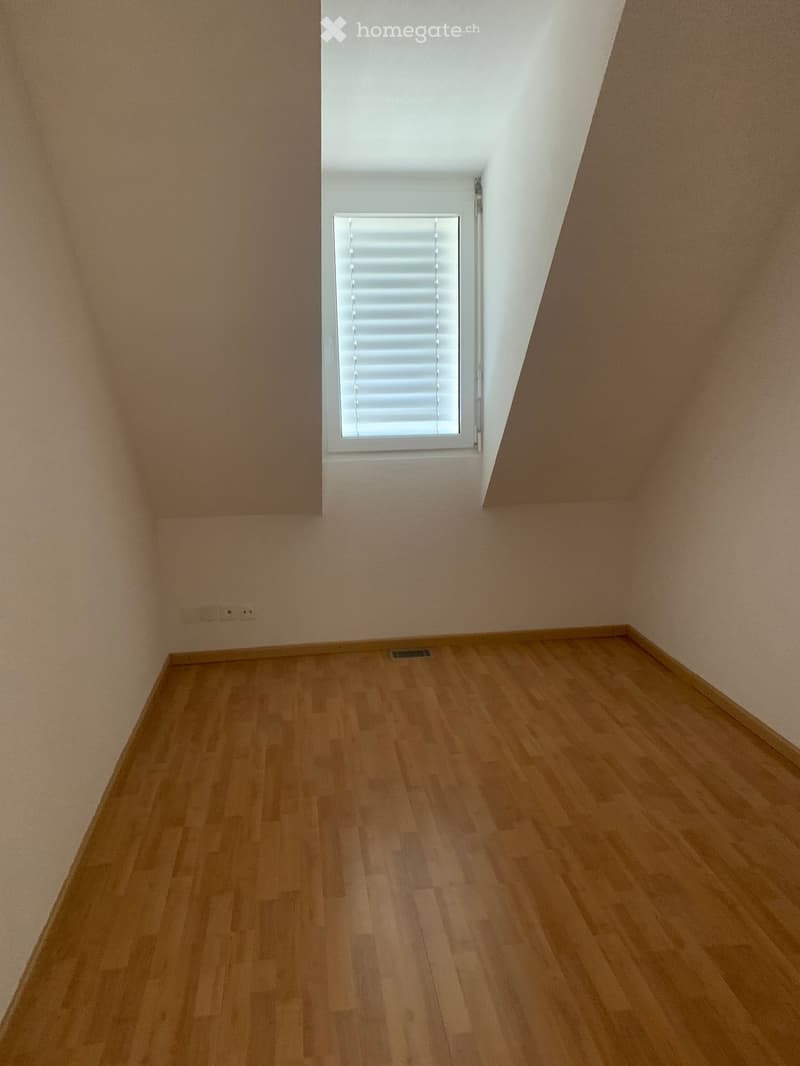Empty room with wooden flooring, white walls, and a single window with blinds.
