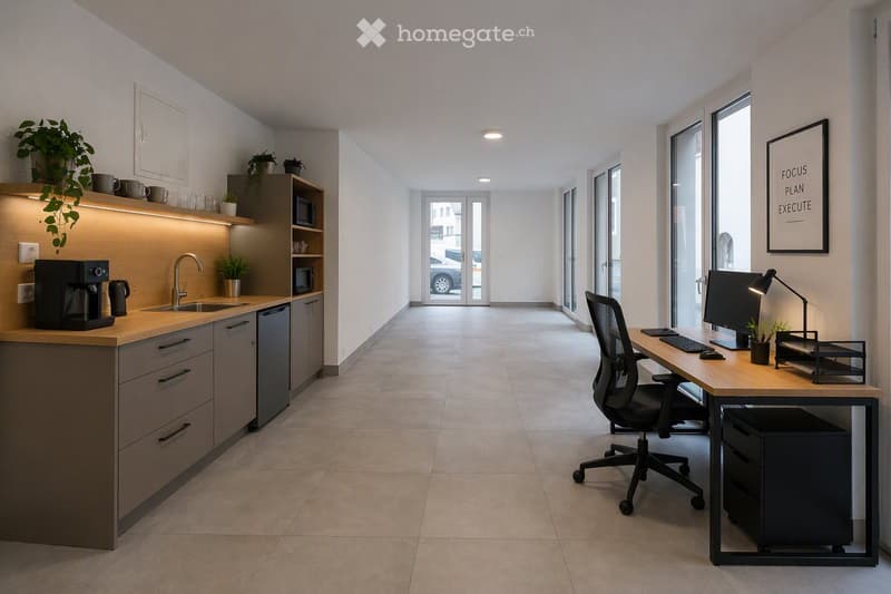Modern, open-plan space with a kitchen area and a workspace. The kitchen features a coffee maker, sink, and cabinets, while the workspace includes a desk, chair, computer, and a framed motivational picture. The room has large windows and a tiled floor.