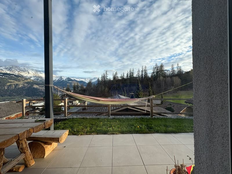 Balcony with tiled floor, wooden table and bench, hammock, and scenic mountain view.