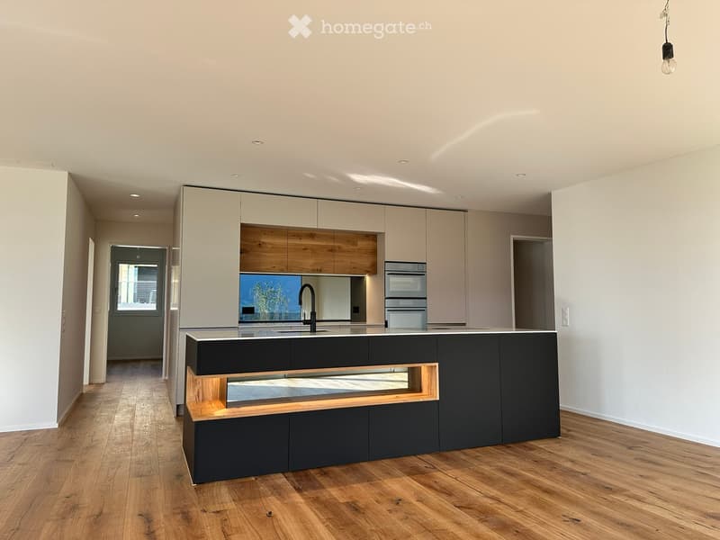 Modern kitchen with light-colored cabinets, dark lower cabinets, a central island, and a sleek sink with a modern faucet. The space features wooden flooring and recessed lighting.