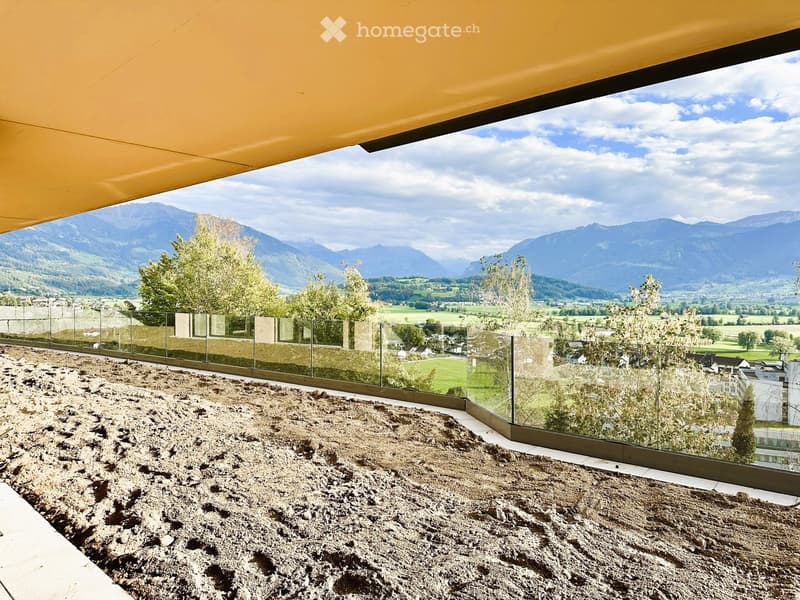 Balcony with glass railing, gravel surface, and scenic mountain view.
