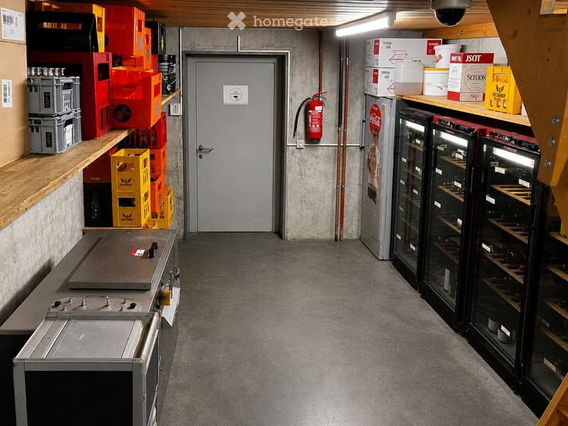 Storage area with industrial shelving, refrigerators, and various storage containers. Includes a fire extinguisher and a door leading to another area.