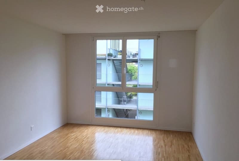 Empty room with wooden flooring and large sliding glass doors leading to a balcony area.
