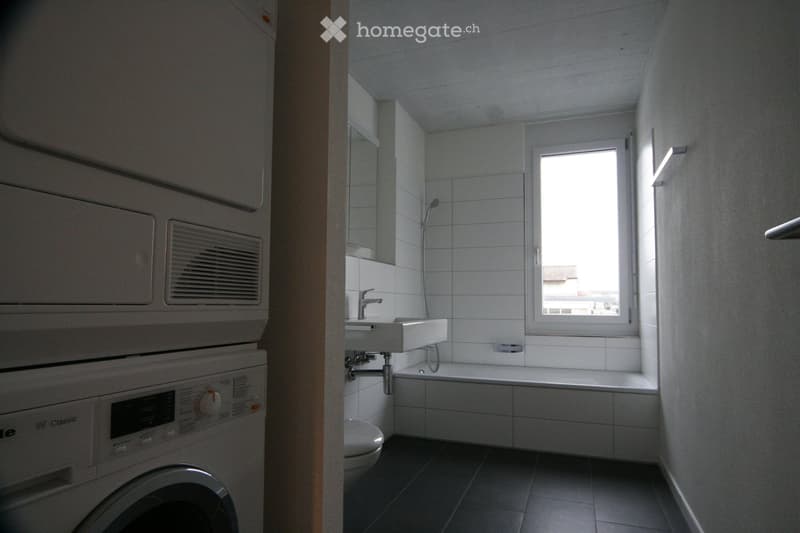 Bathroom with bathtub, shower, toilet, washing machine, and dryer.