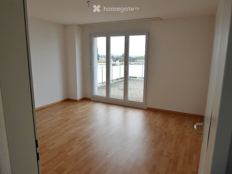 Empty room with wooden flooring, white walls, and large sliding glass doors leading to a balcony.