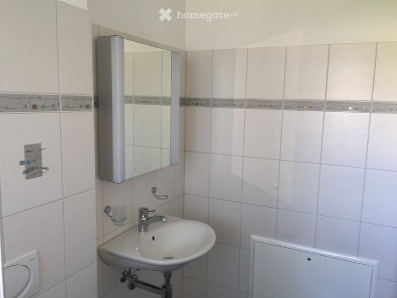 Clean bathroom with white tiles, a sink, a mirror, and a faucet.