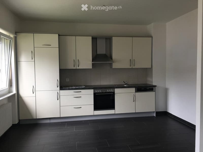 Modern kitchen with white cabinets, stainless steel appliances, and dark tiled flooring.