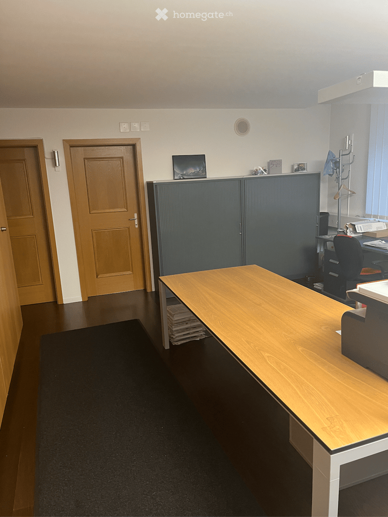 empty room with a desk, two wooden doors, and cabinets against the wall