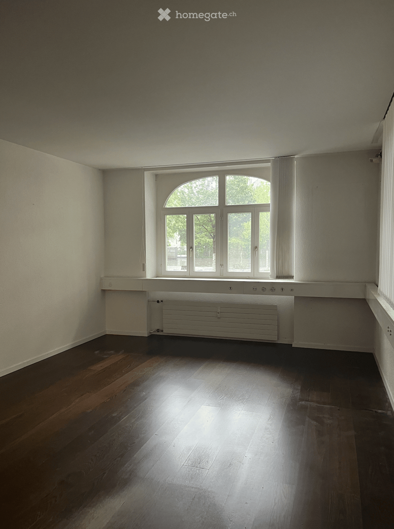 Empty room, white walls, wooden floor, large arched window