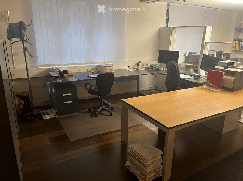 An office with two desks, two chairs, and computer monitors, printer, and various office supplies.