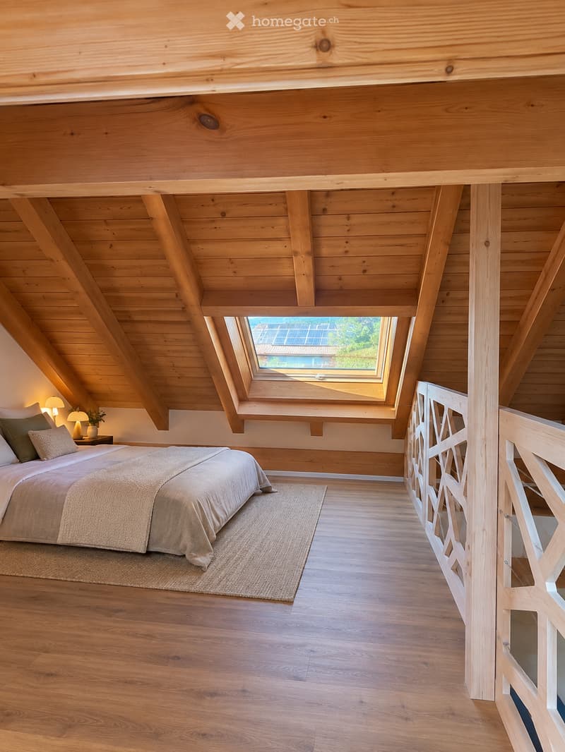Cozy attic bedroom with wooden beams, skylight window, bed with pillows and blankets, nightstand with lamp, and a small potted plant.
