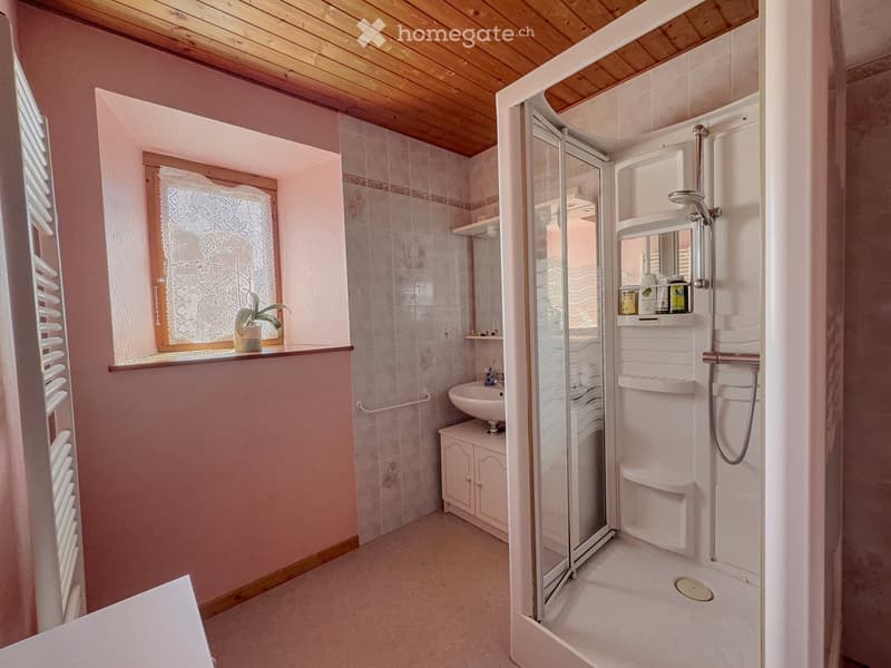 Cozy bathroom with pink walls, wooden ceiling, shower stall, sink, and small window with decorative glass.