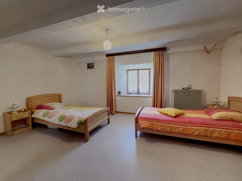 Cozy bedroom with two single beds, colorful bedspreads, nightstands, lamps, and a window with curtains.