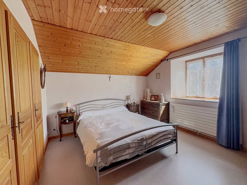 Cozy attic bedroom with wooden slanted ceilings, a metal-framed bed, nightstands, lamps, and a dresser.