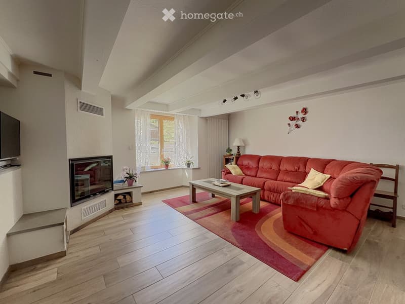 Modern living room with a red sectional sofa, coffee table, fireplace, TV, and decorative plants.
