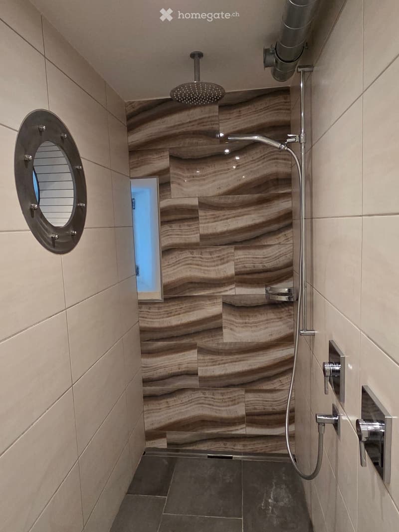 Modern shower area with marble-patterned tiles, a handheld showerhead, and a built-in seat.