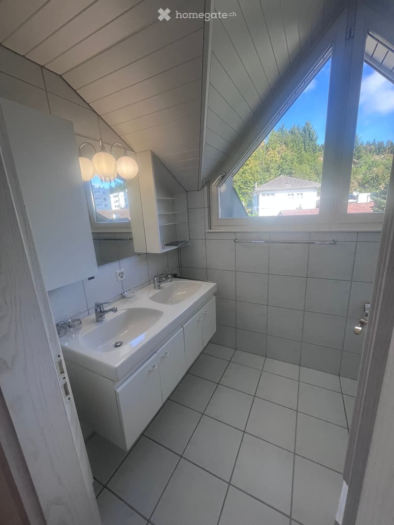 Modern bathroom with double sink, mirrored cabinet, and large windows offering a view of the outdoors.