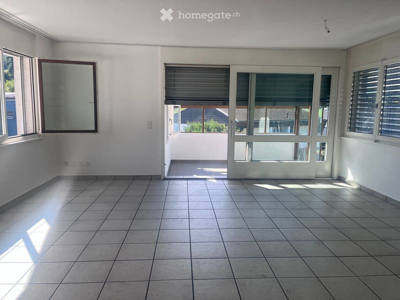 Empty room with tiled floor, white walls, large windows, and a door leading to an outdoor area.