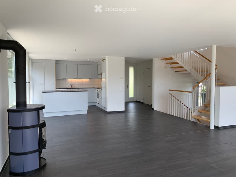 Open-plan kitchen and living area with modern cabinetry, a central island, and a staircase leading to an upper level.