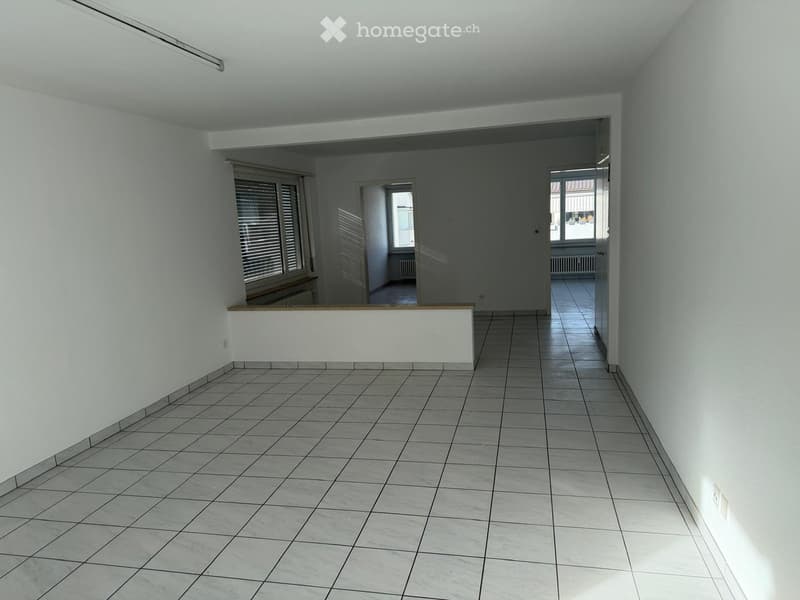 Empty hallway with tiled floor, white walls, and multiple doors leading to other rooms.
