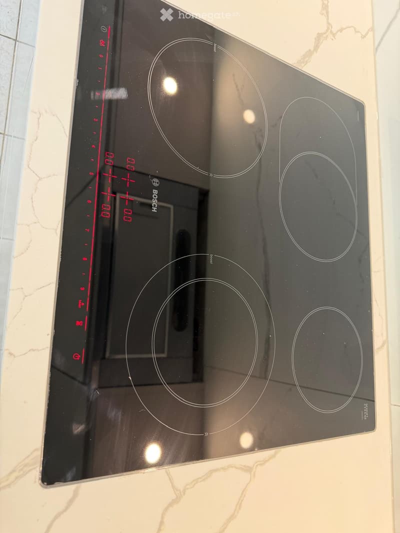 Modern induction cooktop with multiple cooking zones and digital control panel.