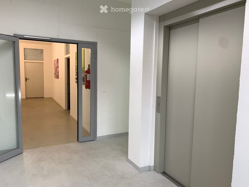 Open doorway, elevator, closed door, fire extinguisher, light on wall, glass door, concrete flooring, white walls