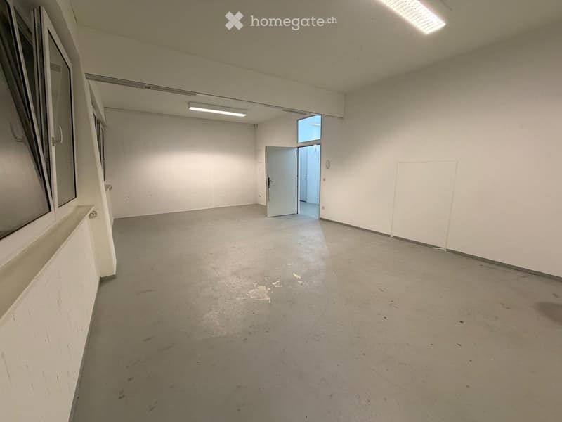 Empty room with bare walls, concrete floor, and a single door leading to another space.
