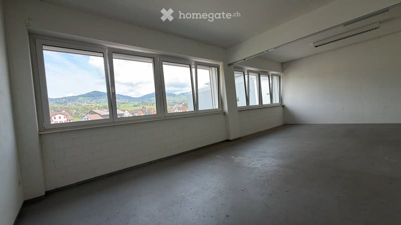 Empty room with white brick walls, large windows, and a concrete floor. No furniture or equipment present.