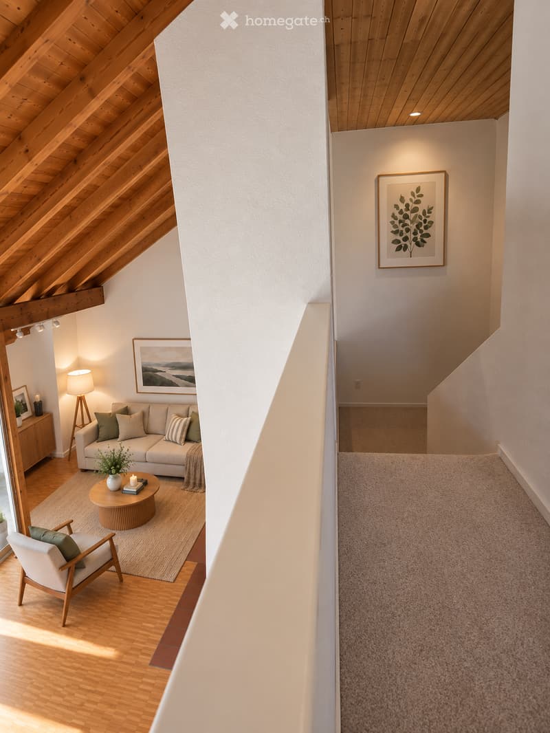 Modern living room with wooden floors, white walls, and exposed wooden beams. Features a sofa, coffee table, armchair, table lamp, and artwork.