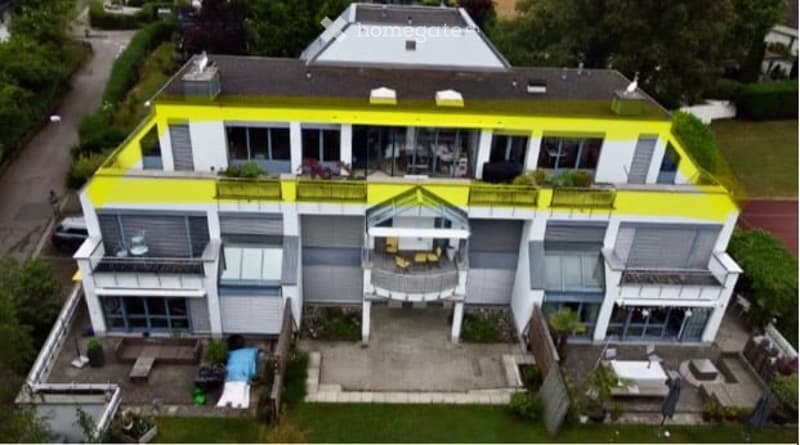 A modern two-story house with a yellow and white exterior, multiple balconies, large windows, and a well-maintained garden area.