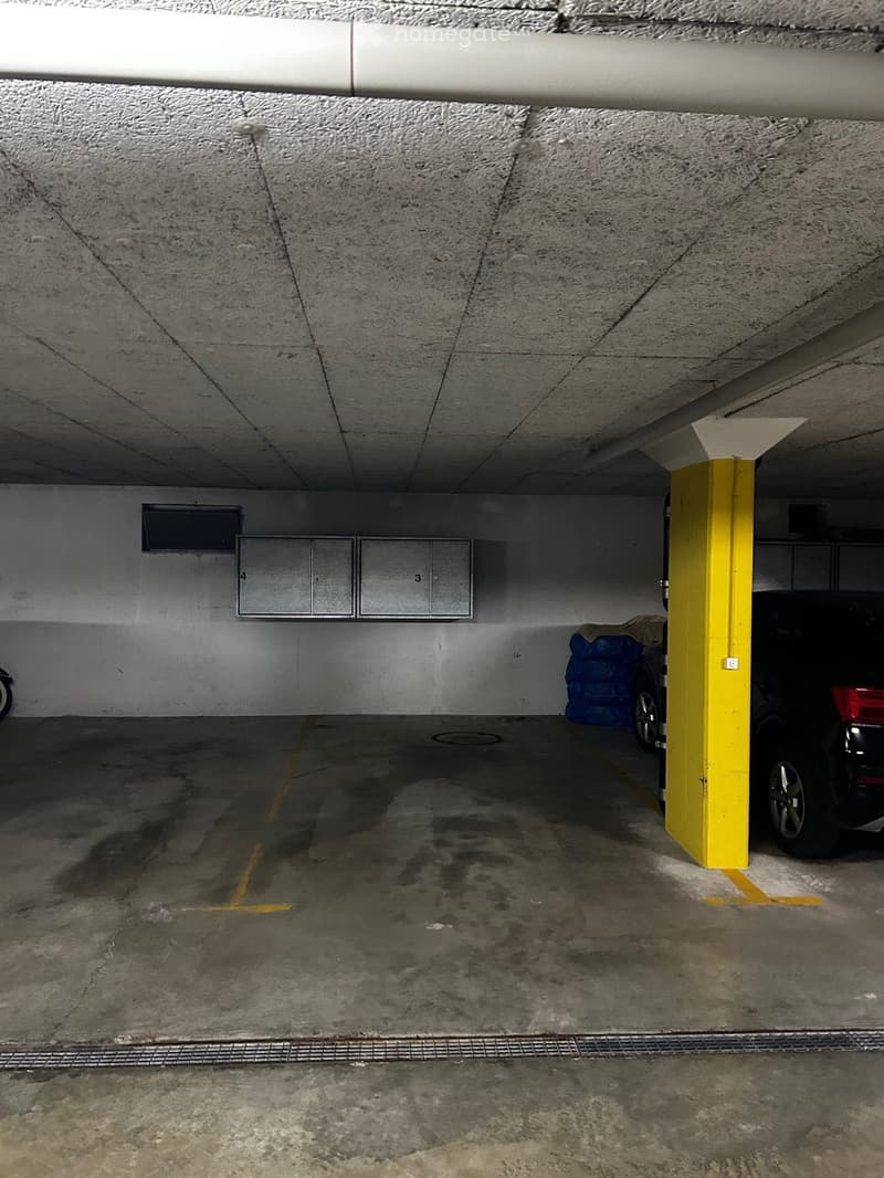 underground parking lot, white walls, yellow and white markings on the floor, yellow and white columns, 2 metal lockers