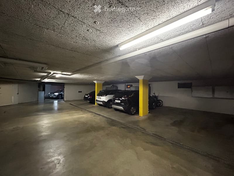 empty underground parking lot, four cars, two scooters, yellow pillars