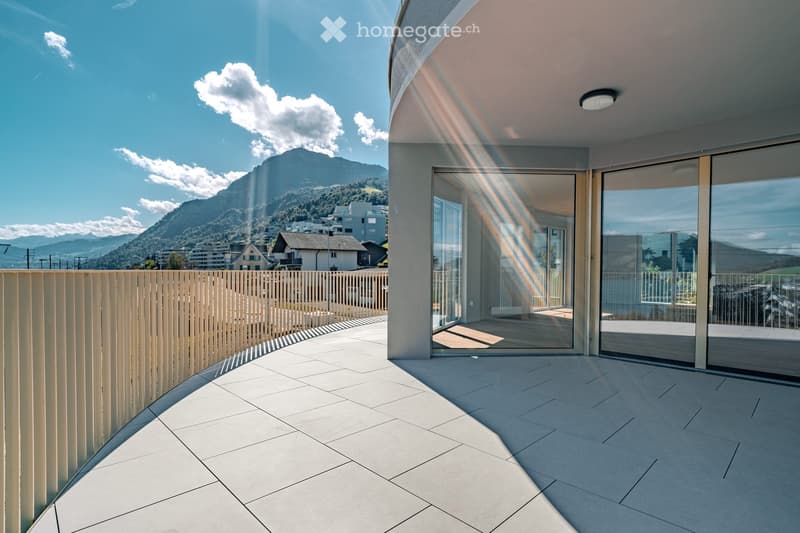 Modern balcony with large glass sliding doors, tiled floor, wooden fence, and scenic mountain view.