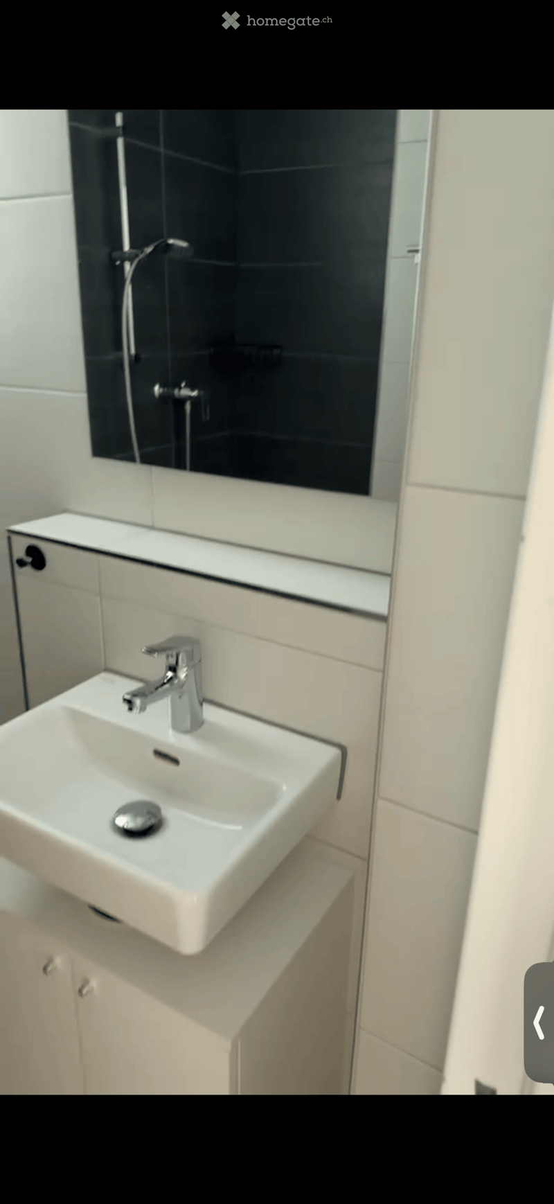 Modern bathroom with a white sink, chrome faucet, and built-in cabinetry. The sink is mounted on a countertop with a sleek design, and the background features a large mirror with a black frame.