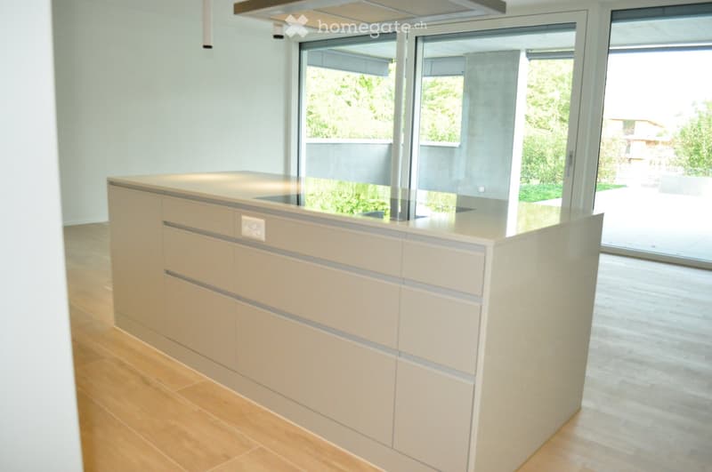 Modern reception area with a sleek, light-colored reception desk, large glass windows, and wooden flooring.