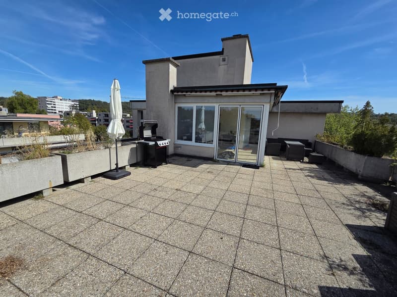 Roof terrace with tiled flooring, umbrella, grill, seating area, and surrounding greenery.