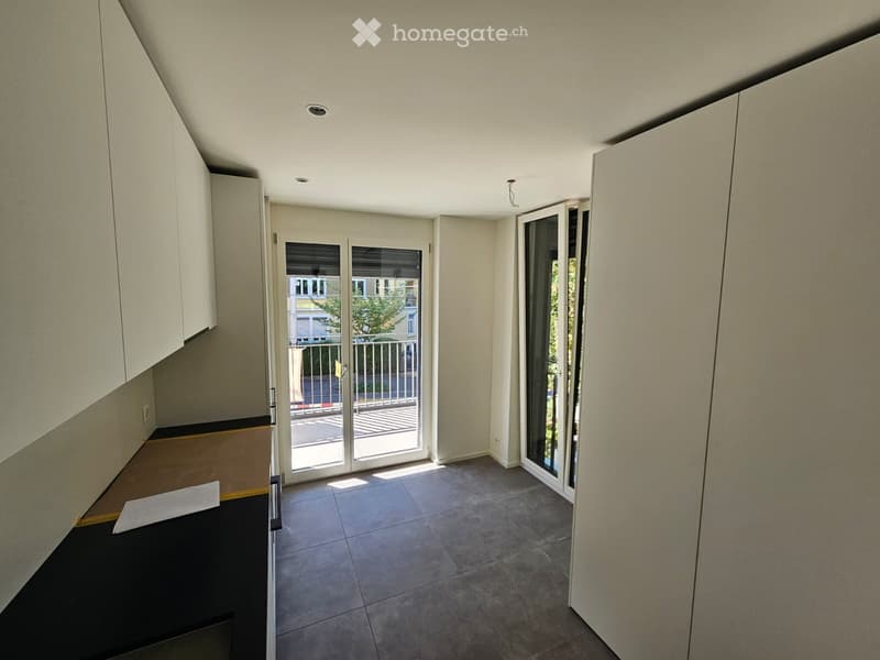 Empty room with tiled floor, white walls, and sliding glass door leading to a balcony.