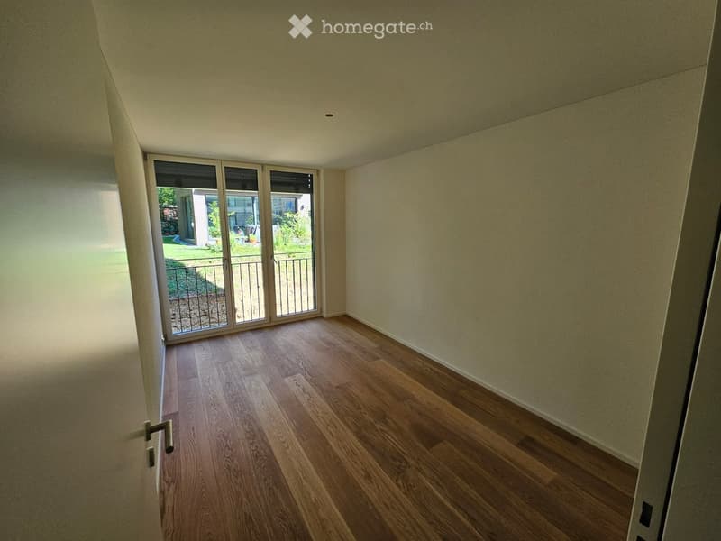 Empty room with wooden flooring, light-colored walls, and large sliding glass doors leading to a balcony or outdoor area.