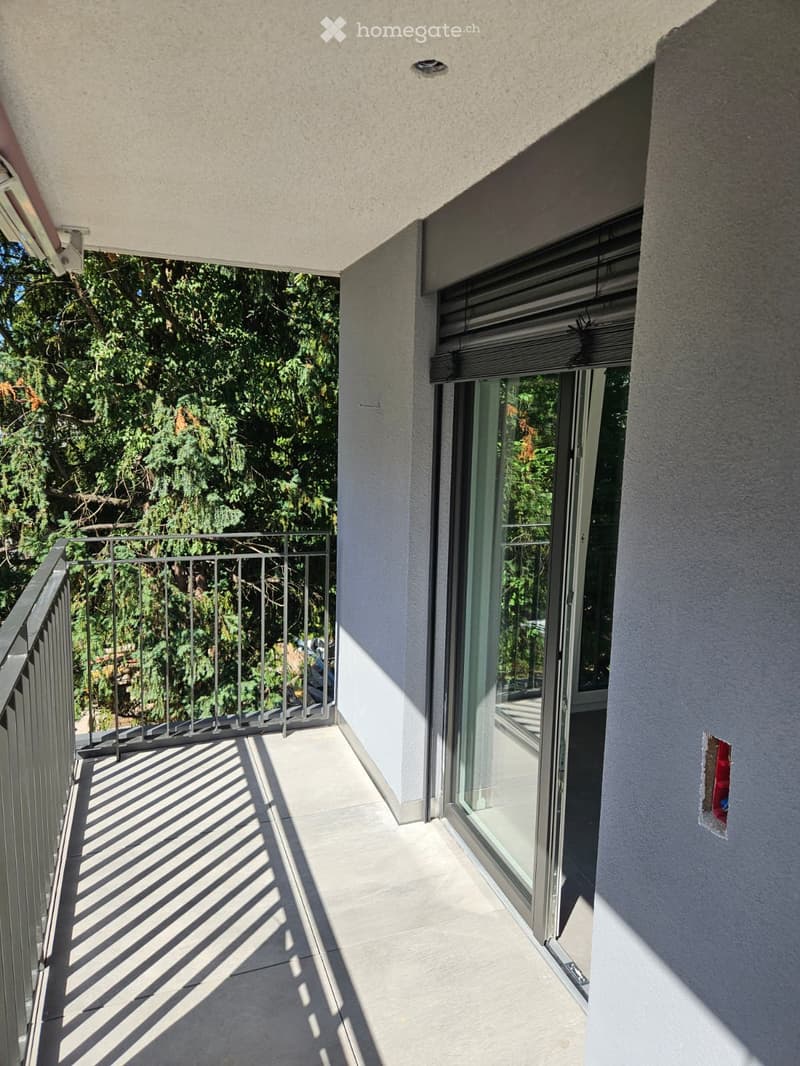 Balcony with a metal railing, tiled floor, and large glass sliding doors leading to the interior.