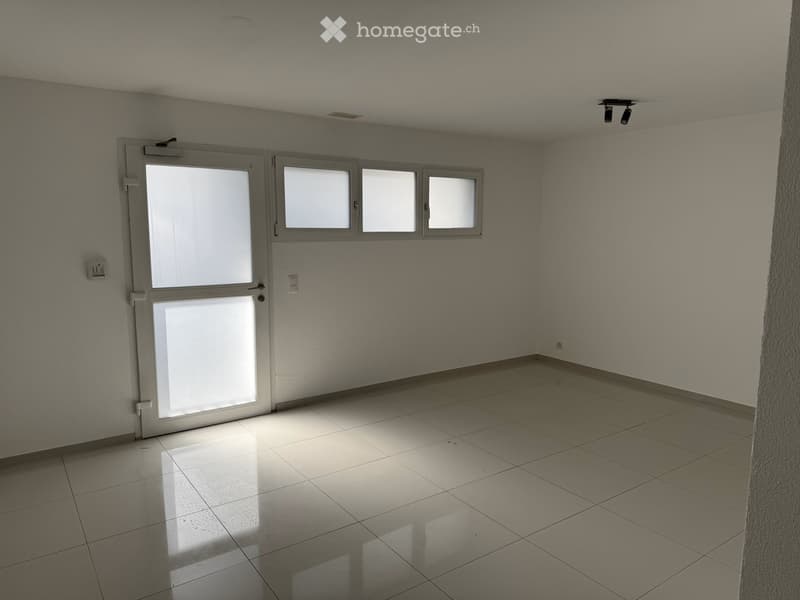 Empty room with tiled floor, white walls, and a door with glass panels. No furniture or equipment is present.