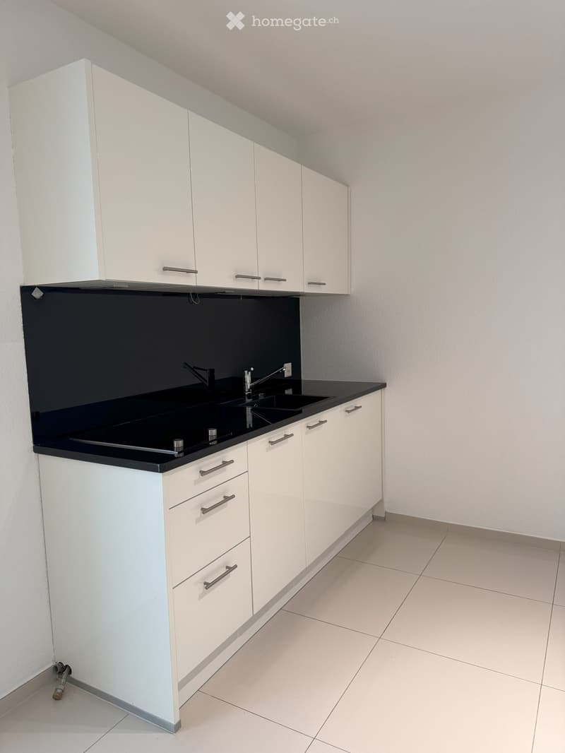 Modern kitchen with white cabinets, black countertop, and a double sink with a modern faucet.