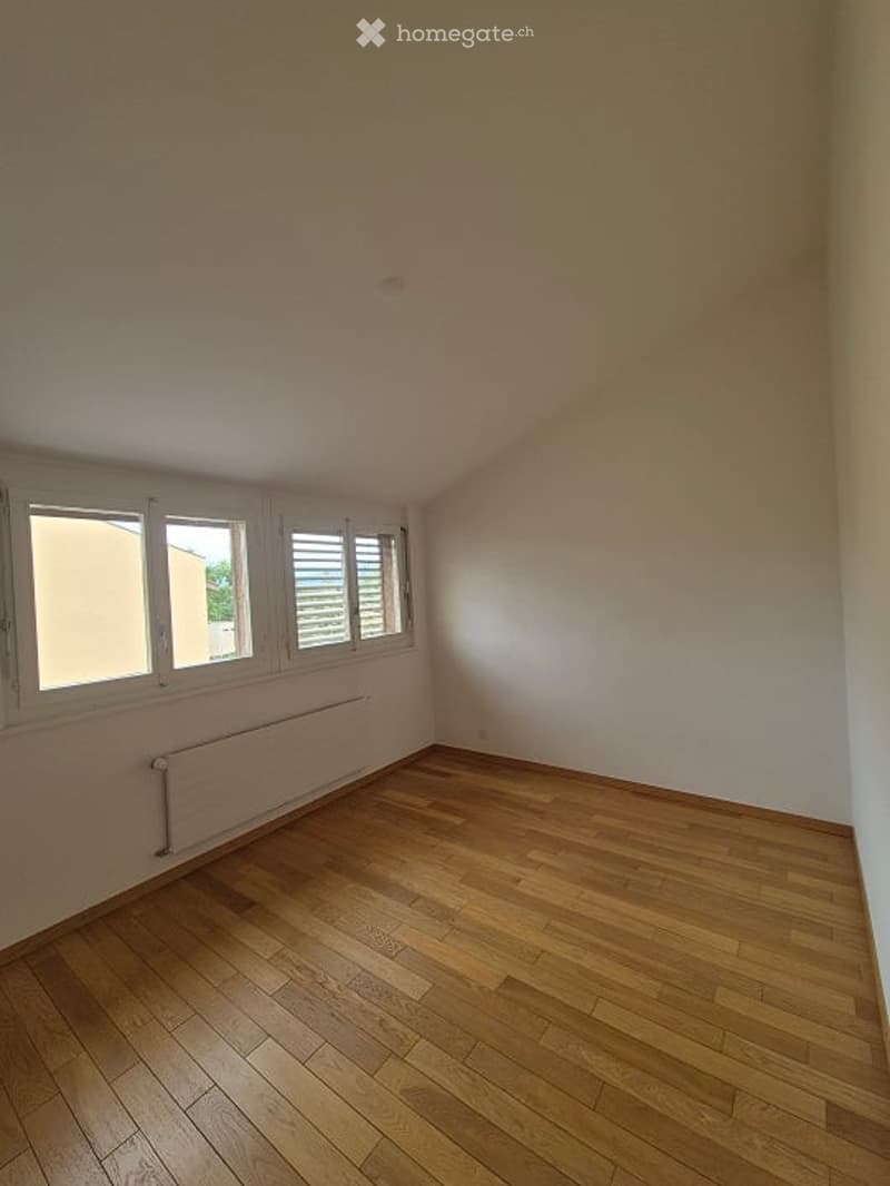 Completely empty room with wooden flooring, white walls, and large windows with shutters. No furniture or equipment present.