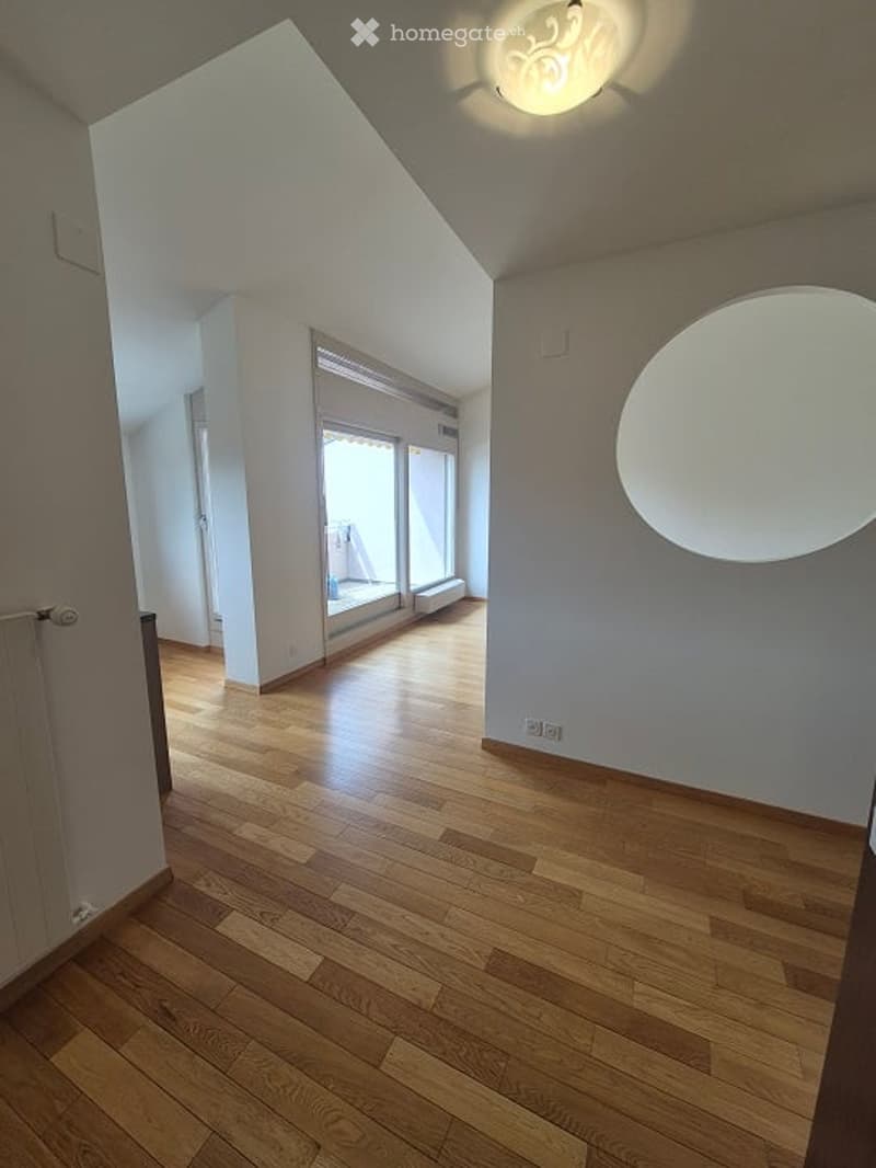 Empty room with wooden flooring, white walls, and large windows leading to a balcony. No furniture or equipment visible.