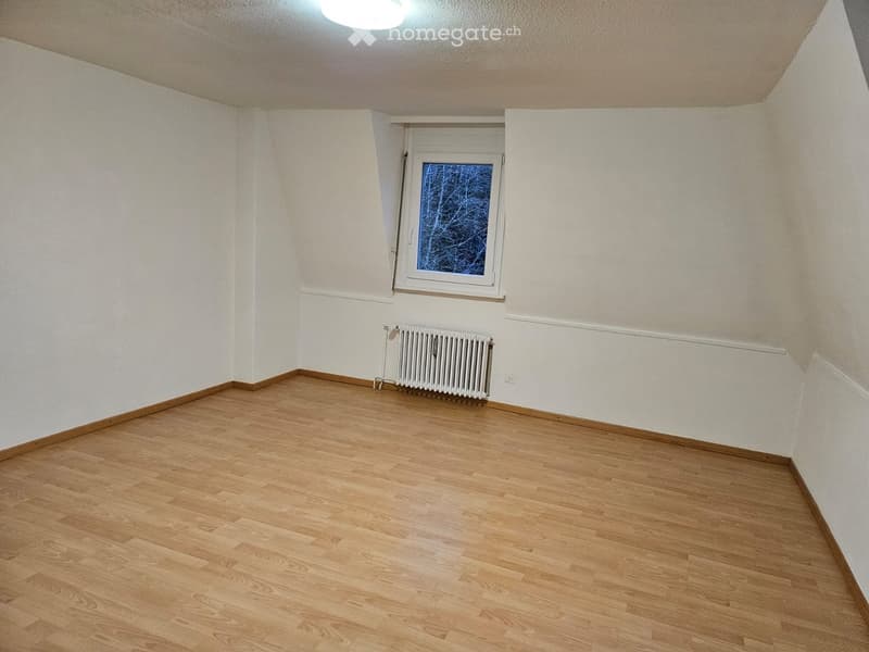 Empty room with wooden flooring, white walls, a single window, and a radiator.