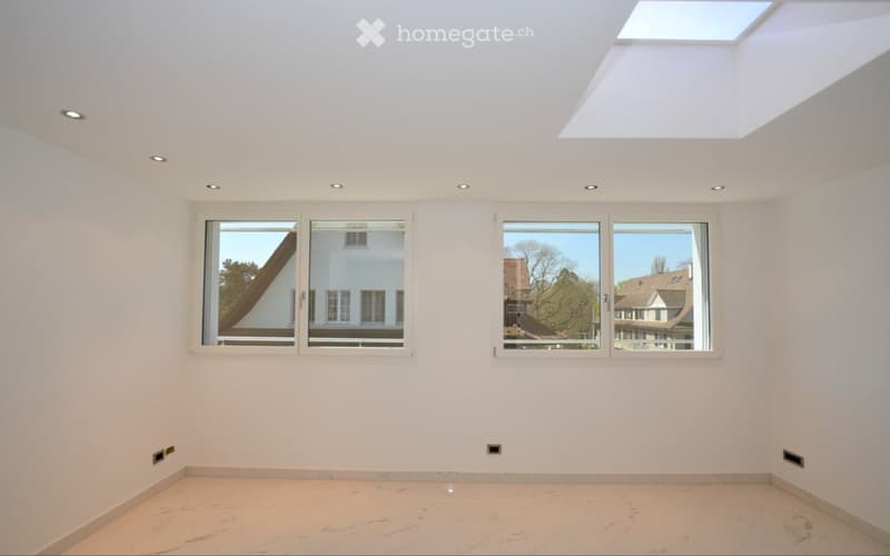 Empty room with white walls, light-colored tiled floor, large windows, and a skylight. No furniture or equipment present.